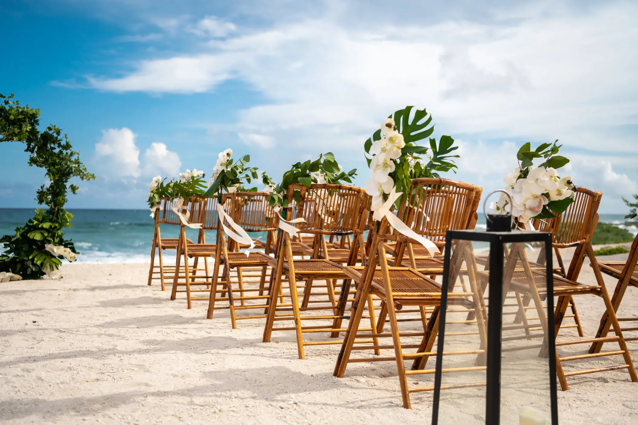 Beachfront wedding ceremony with bamboo chairs and white orchids at Grand Sirenis, Riviera Maya