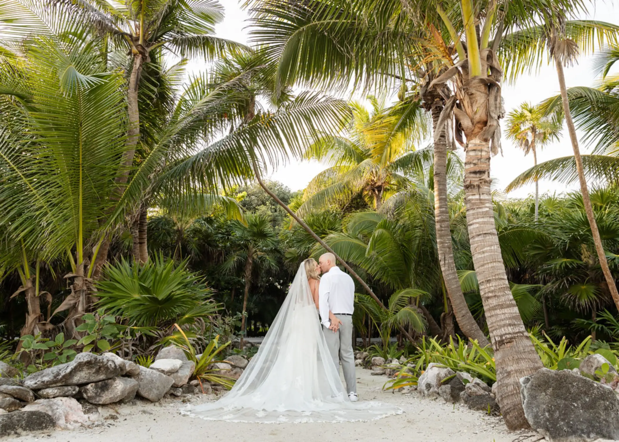 The bride and groom standing on a tropical path at Grand Sirenis Riviera Maya