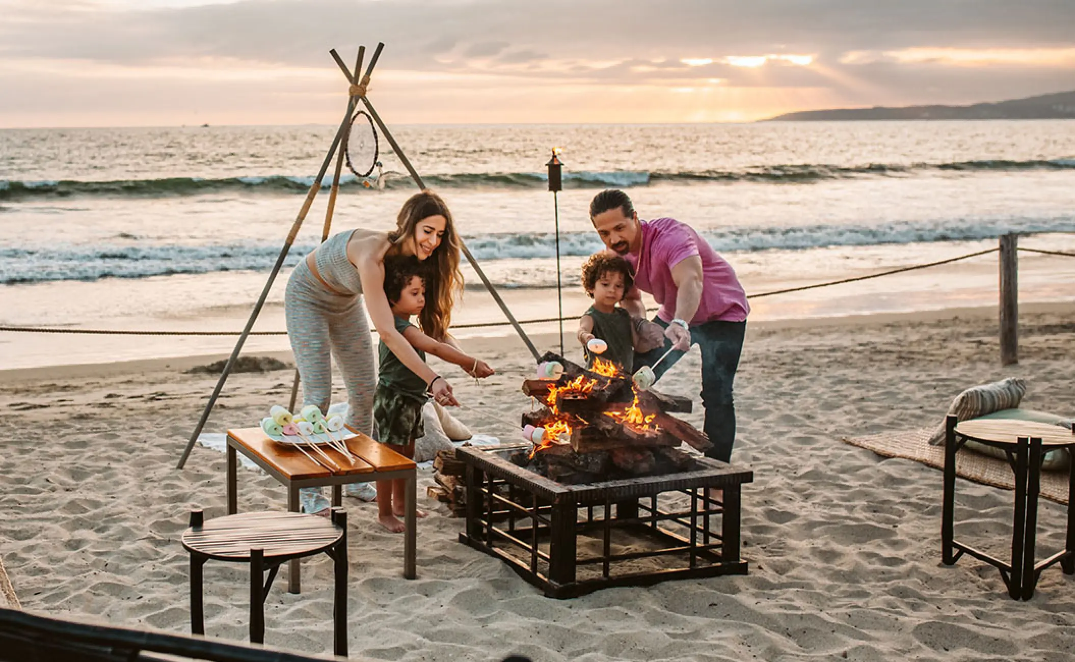 Family roasting marshmallows over a beach fire pit at Grand Velas Riviera Nayarit, Puerto Vallarta