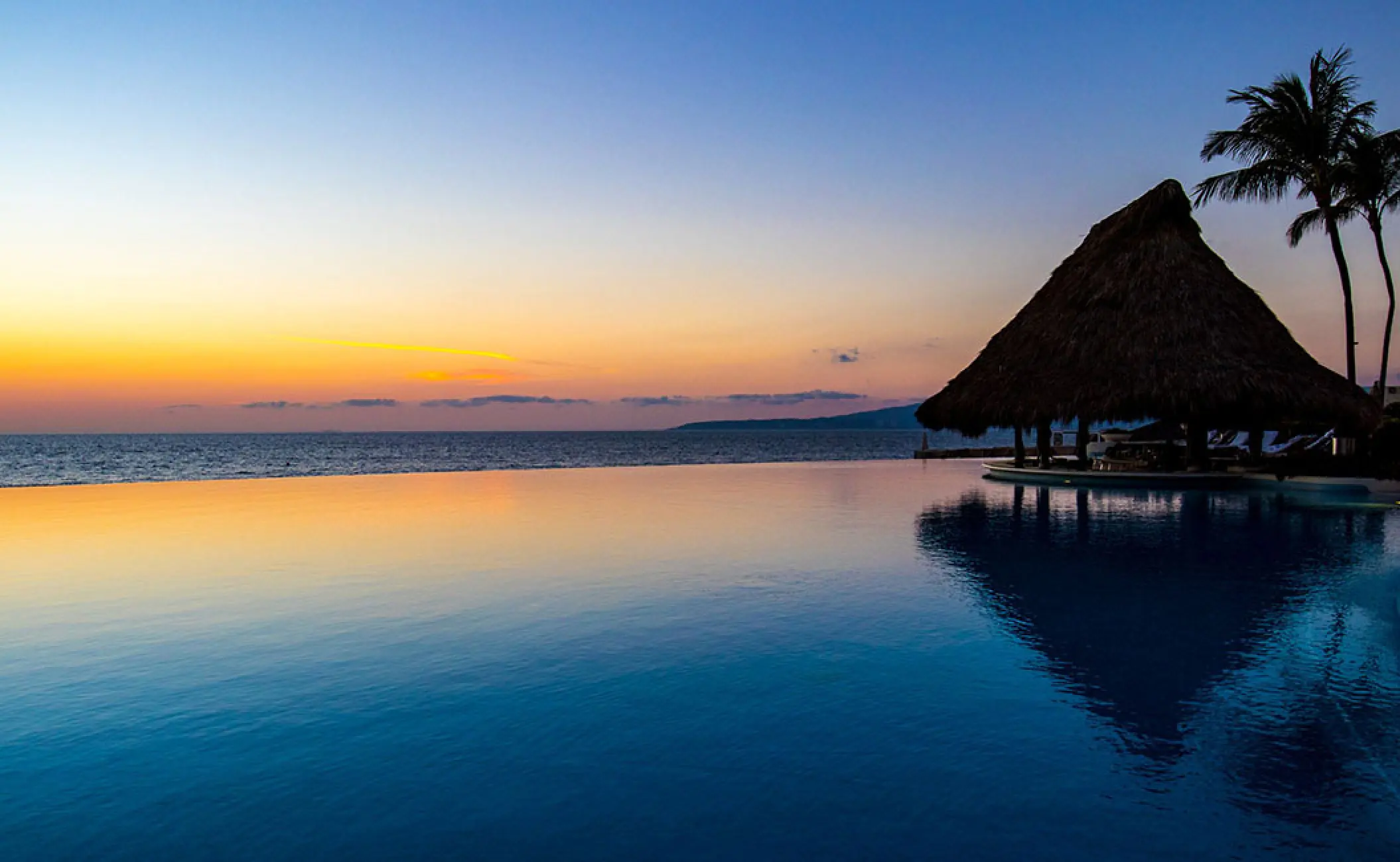 Grand Velas Riviera Nayarit infinity pool and thatched palapa at sunset, Puerto Vallarta