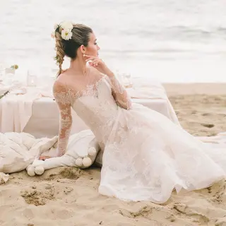 Bride sitting on the sand by a beach reception table at Grand Velas Riviera Nayarit, Puerto Vallarta