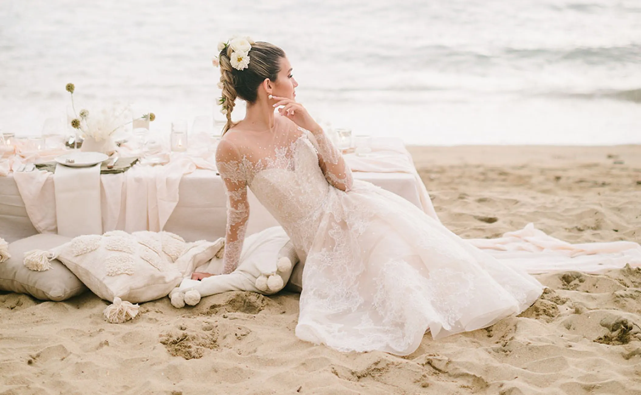 Bride sitting on the sand by a beach reception table at Grand Velas Riviera Nayarit, Puerto Vallarta