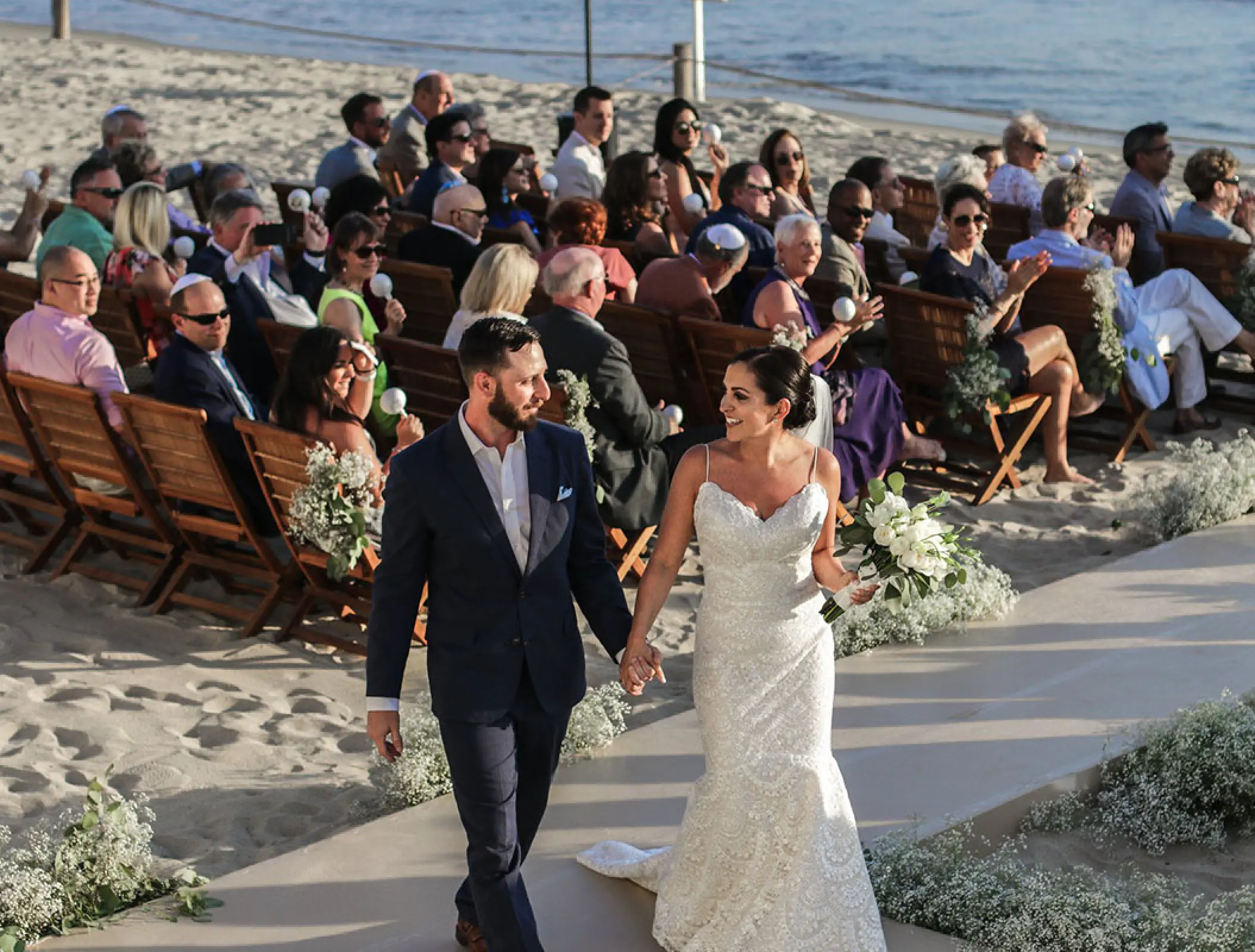 Newlyweds walking down the aisle at a beach ceremony at Grand Velas Riviera Nayarit, Puerto Vallarta