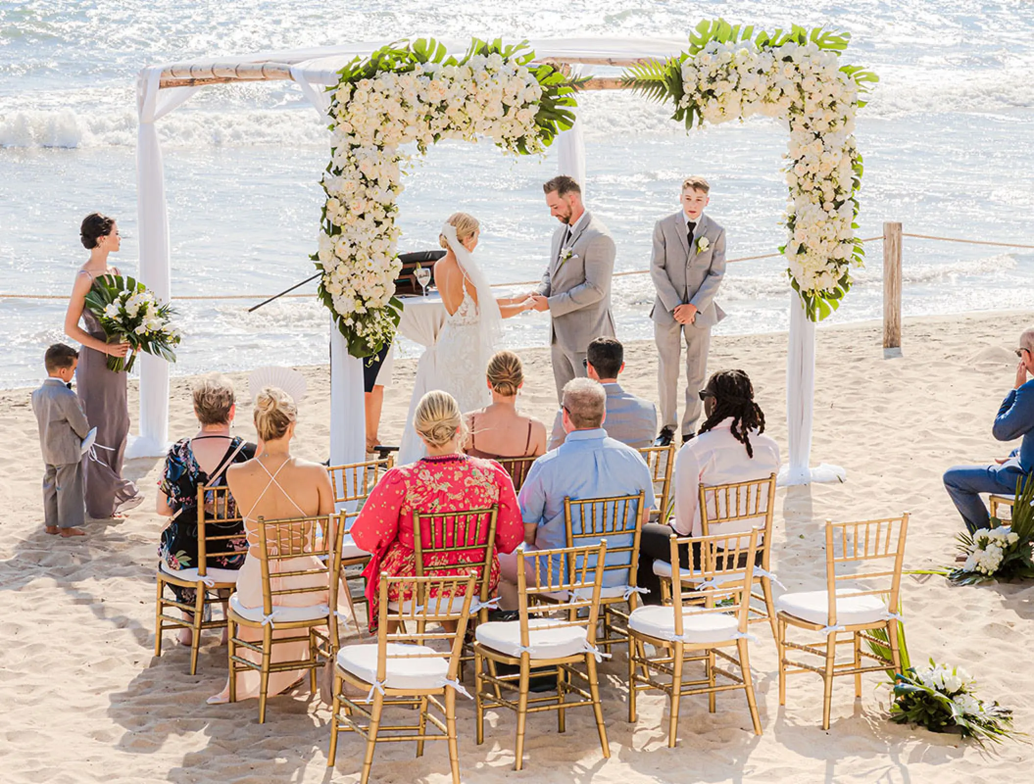 Beachfront wedding ceremony with white floral arch at Grand Velas Riviera Nayarit, Puerto Vallarta