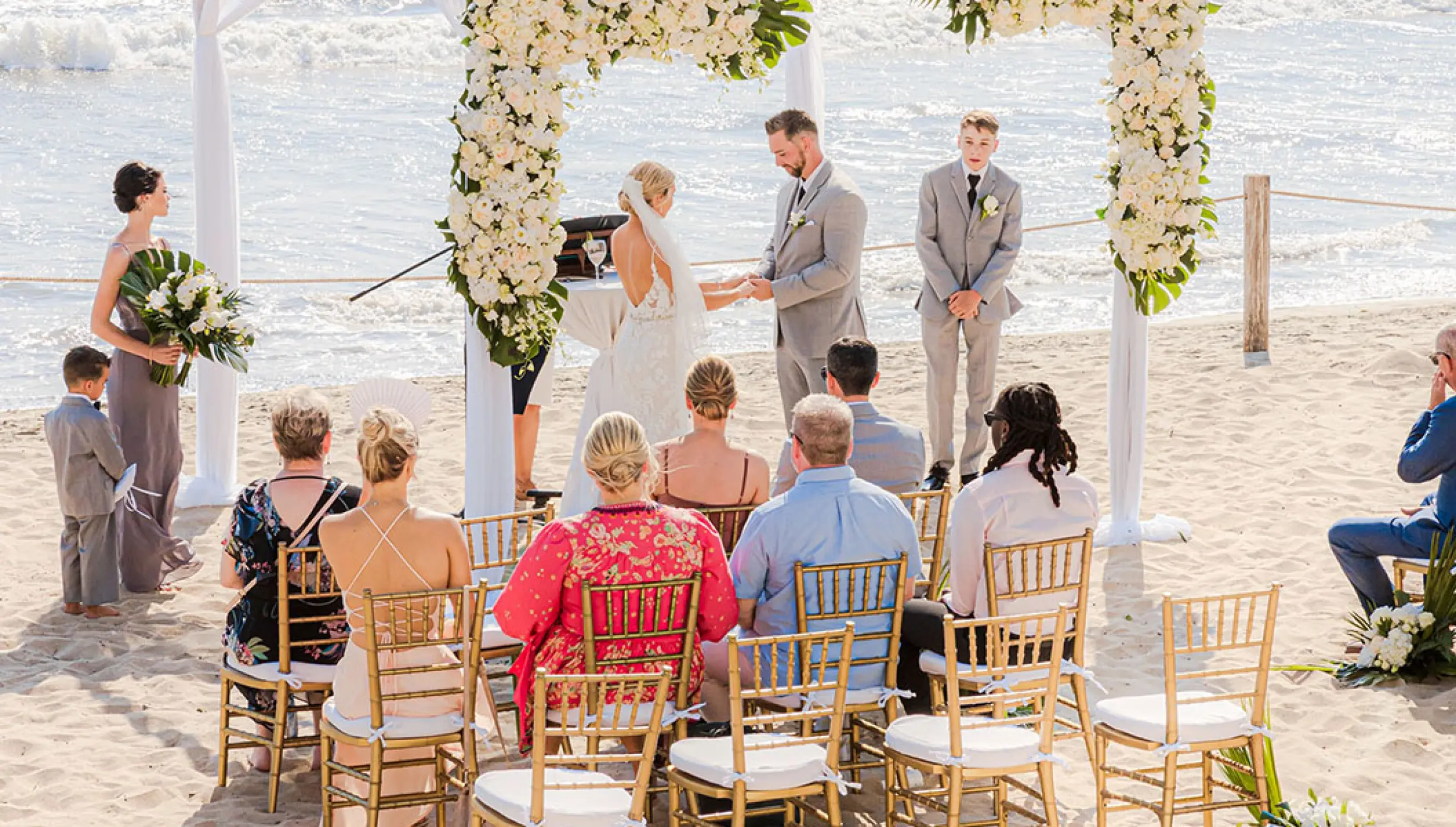 Beachfront wedding ceremony with white floral arch at Grand Velas Riviera Nayarit, Puerto Vallarta