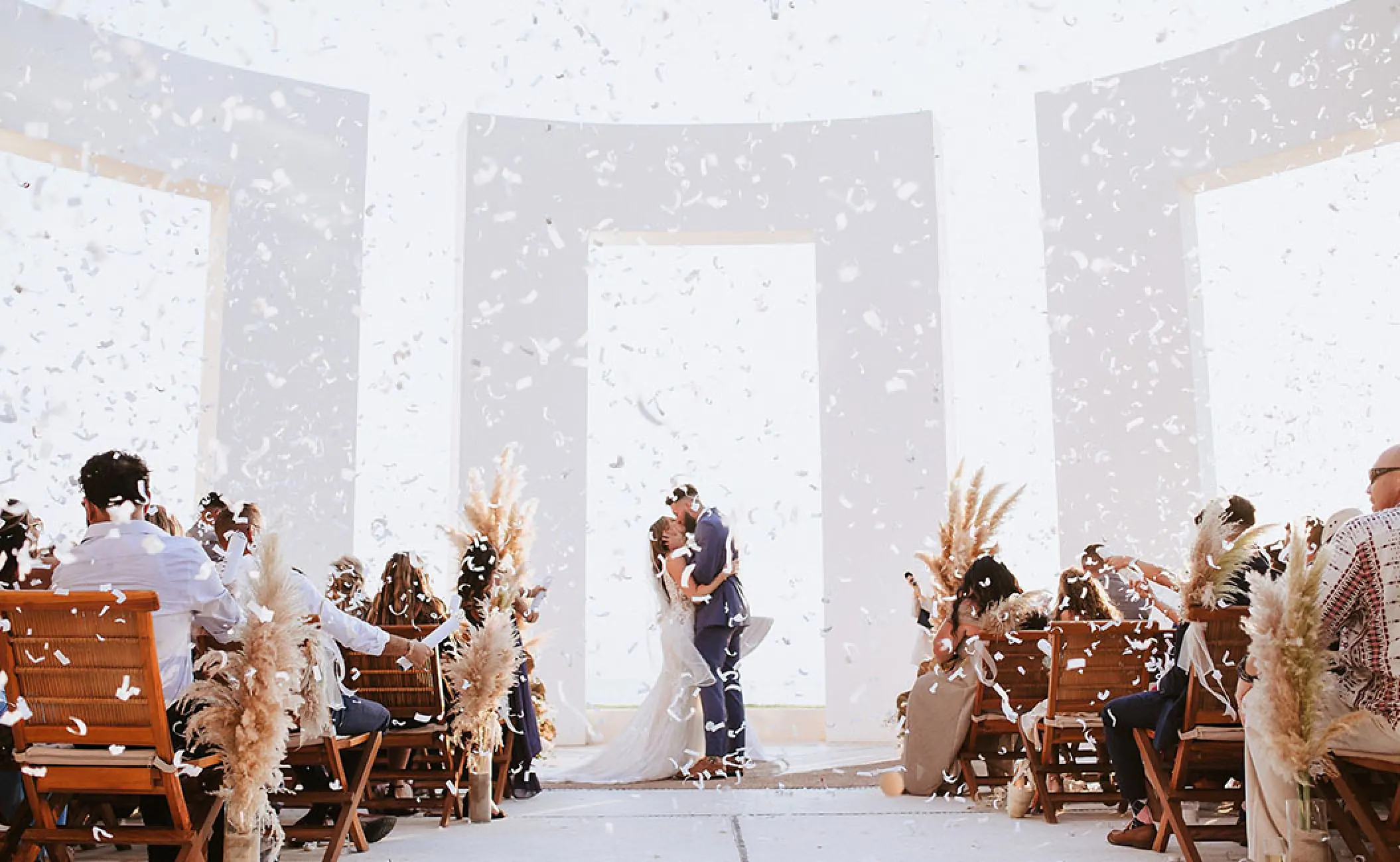 Bride and groom kissing under confetti during their wedding ceremony at Grand Velas Riviera Nayarit, Puerto Vallarta