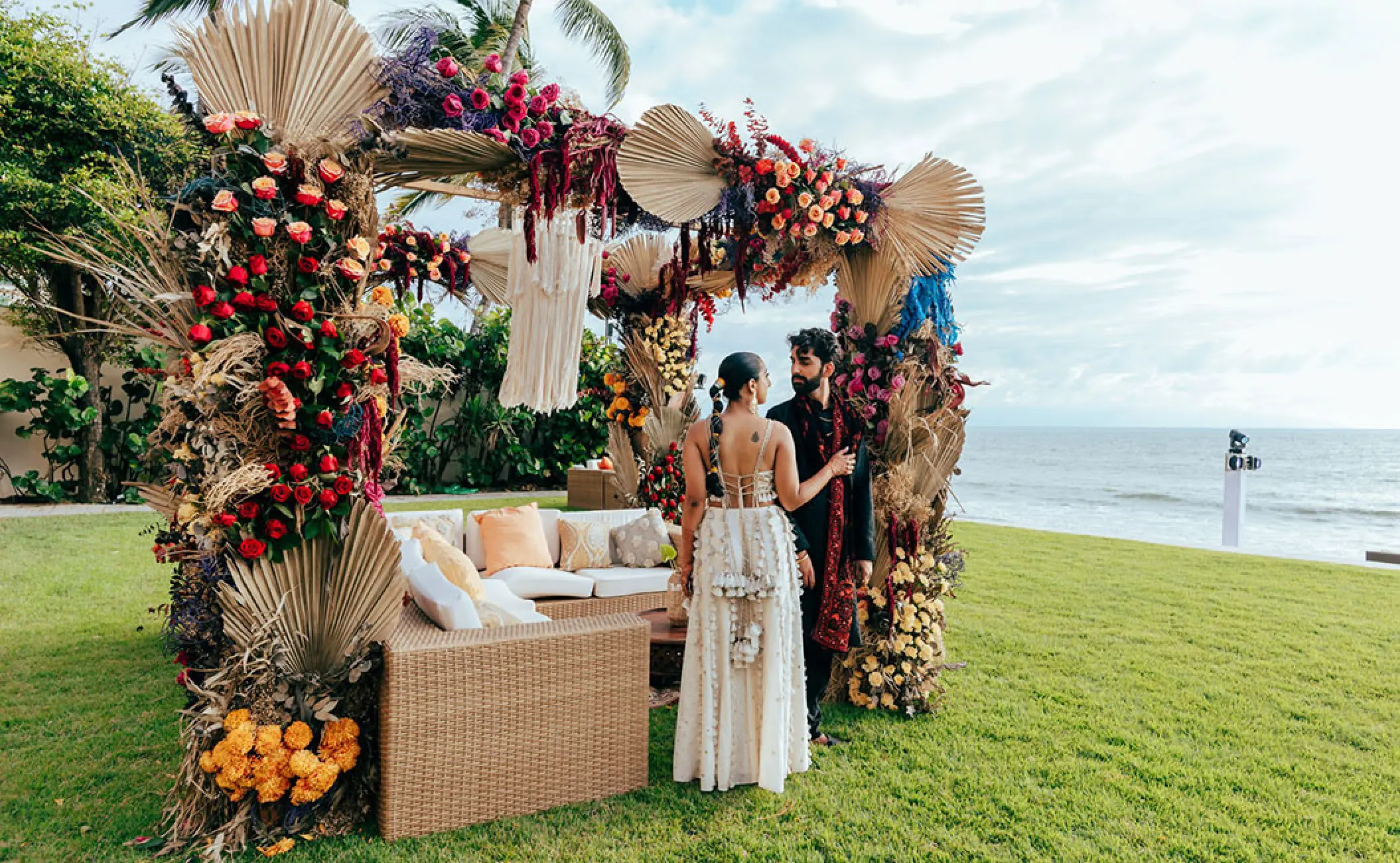 The bride and groom standing by a floral wedding lounge at Grand Velas Riviera Nayarit, Puerto Vallarta