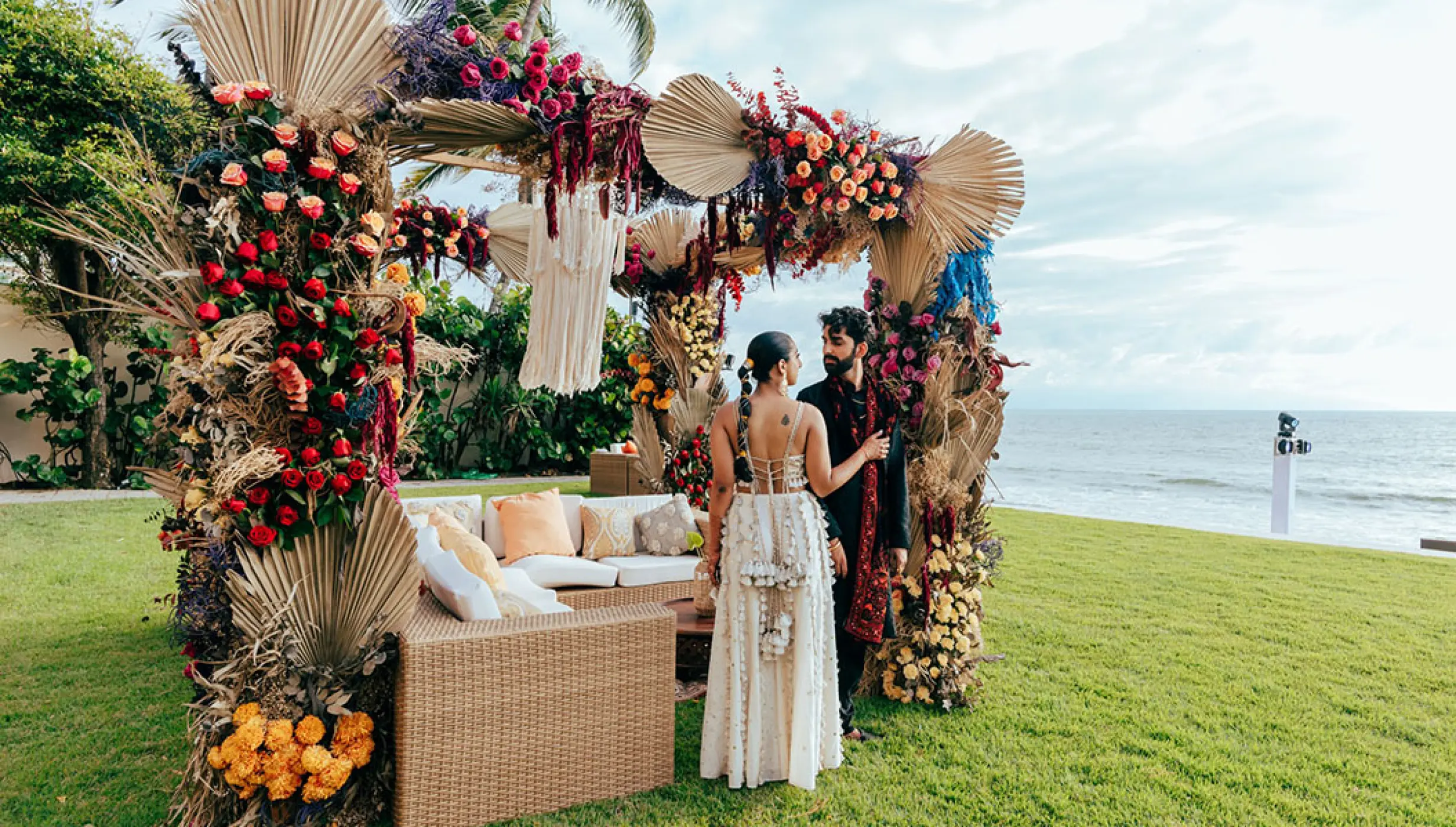 The bride and groom standing by a floral wedding lounge at Grand Velas Riviera Nayarit, Puerto Vallarta