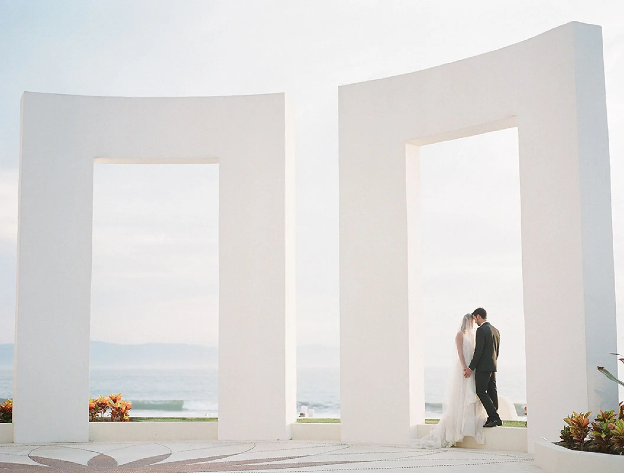 The bride and groom posing under a large white archway at Grand Velas Riviera Nayarit, Puerto Vallarta