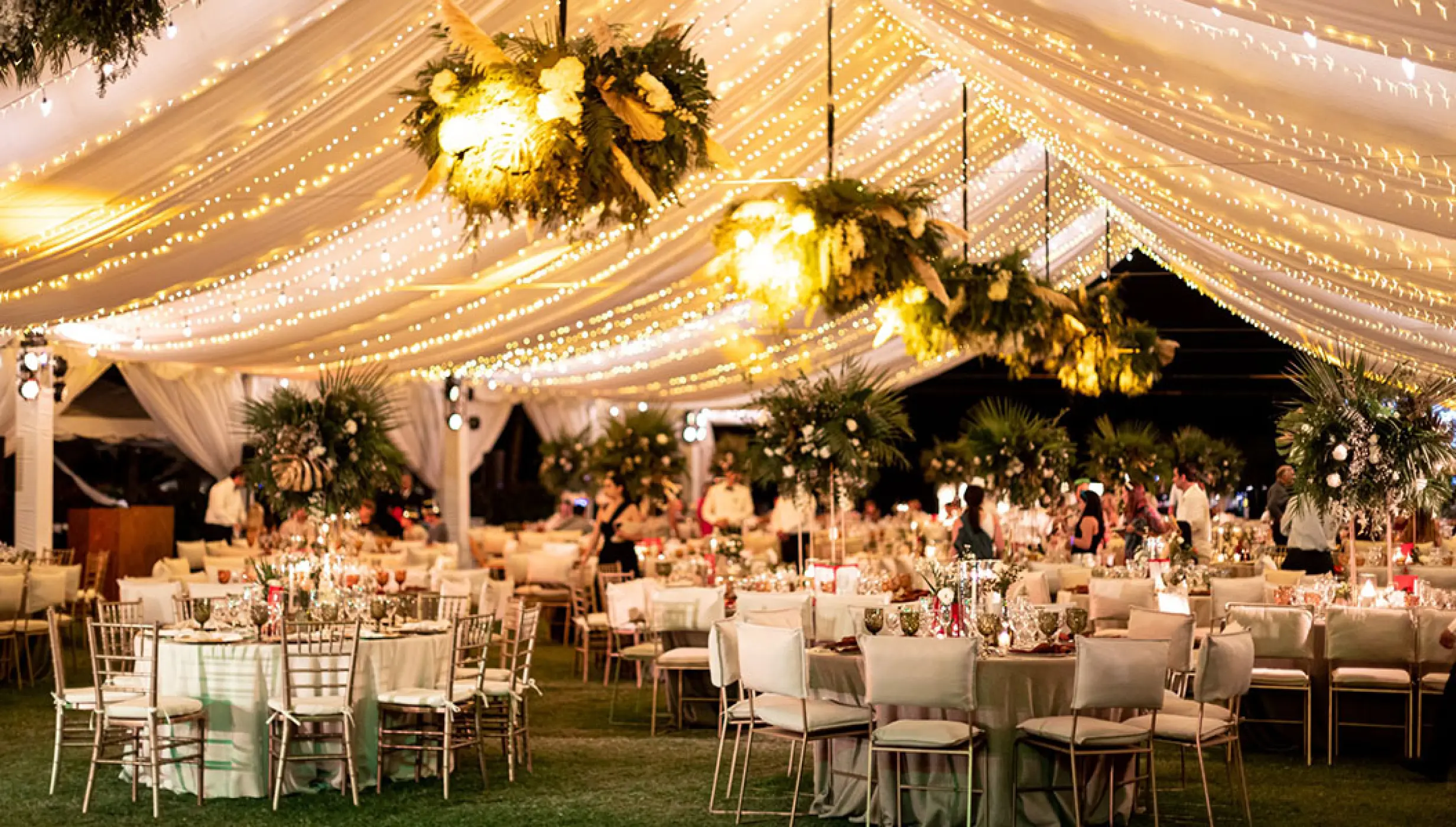Tented wedding reception under fairy lights and floral chandeliers at Grand Velas Riviera Nayarit, Puerto Vallarta