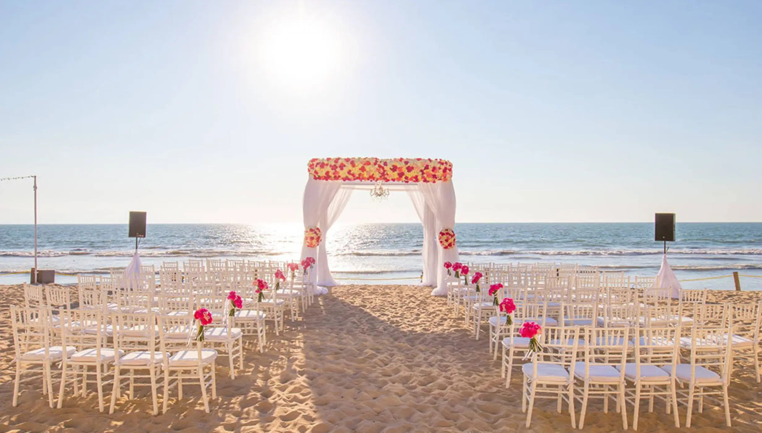 Beachfront wedding ceremony with a floral arch and white chairs at Grand Velas Riviera Nayarit, Puerto Vallarta