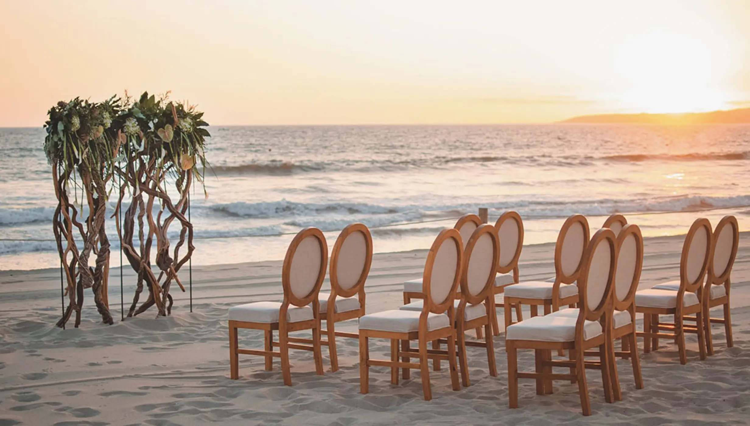 Beachfront wedding ceremony with driftwood arch and wooden chairs at Grand Velas Riviera Nayarit, Puerto Vallarta