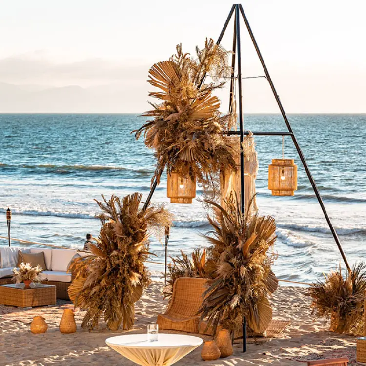 Beachfront wedding reception setup with pampas grass and triangular arch at Grand Velas Riviera Nayarit, Puerto Vallarta