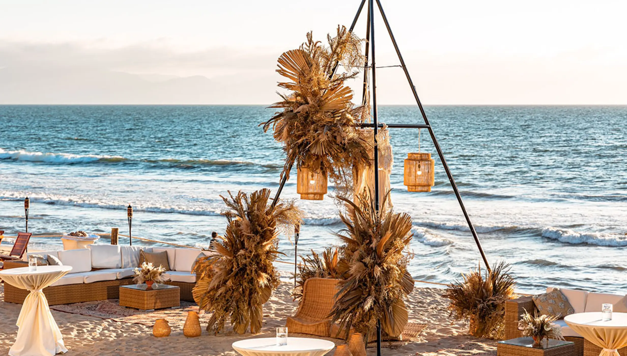 Beachfront wedding reception setup with pampas grass and triangular arch at Grand Velas Riviera Nayarit, Puerto Vallarta