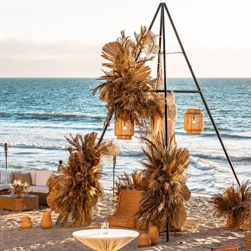 Beachfront wedding reception setup with pampas grass and triangular arch at Grand Velas Riviera Nayarit, Puerto Vallarta