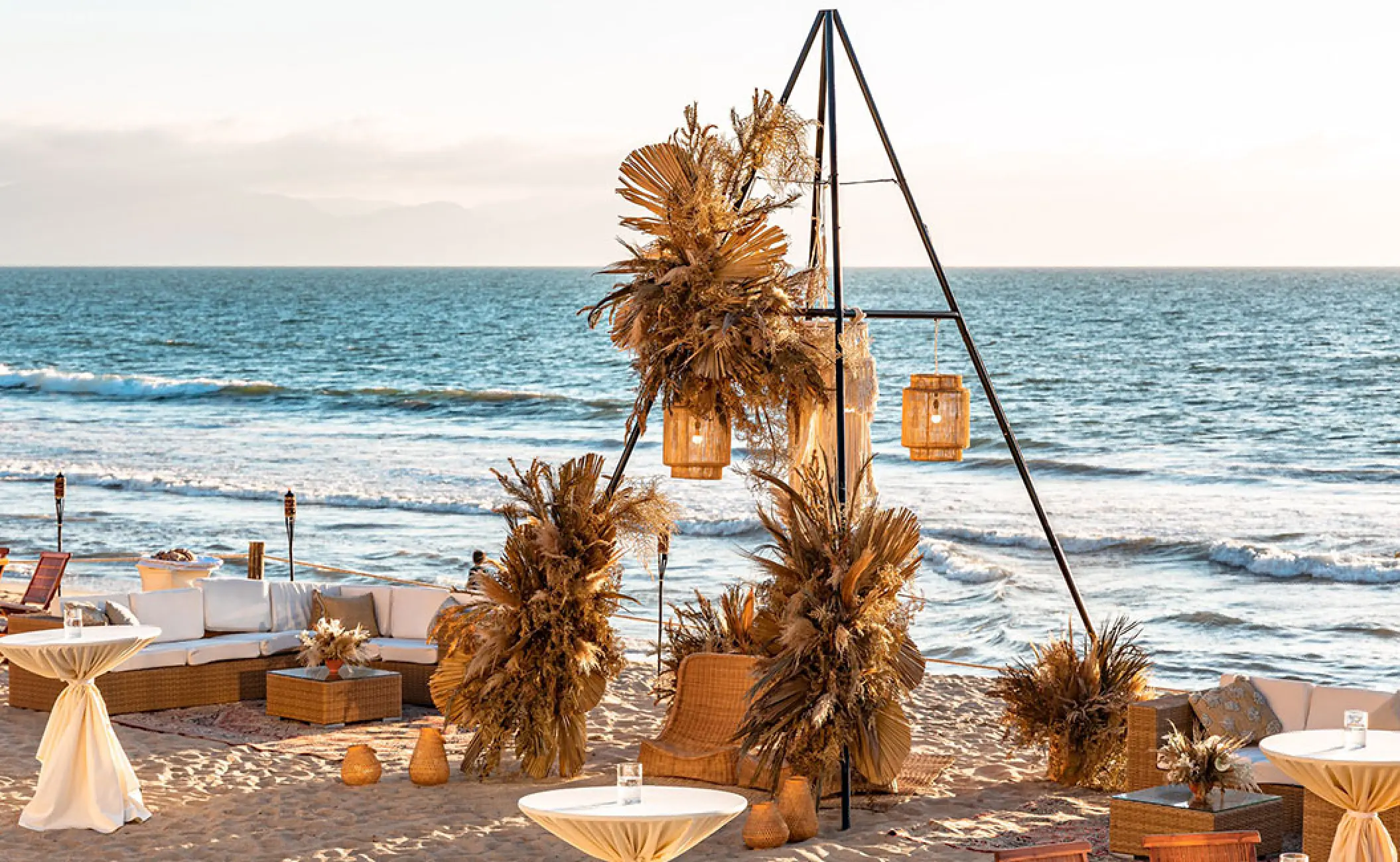 Beachfront wedding reception setup with pampas grass and triangular arch at Grand Velas Riviera Nayarit, Puerto Vallarta