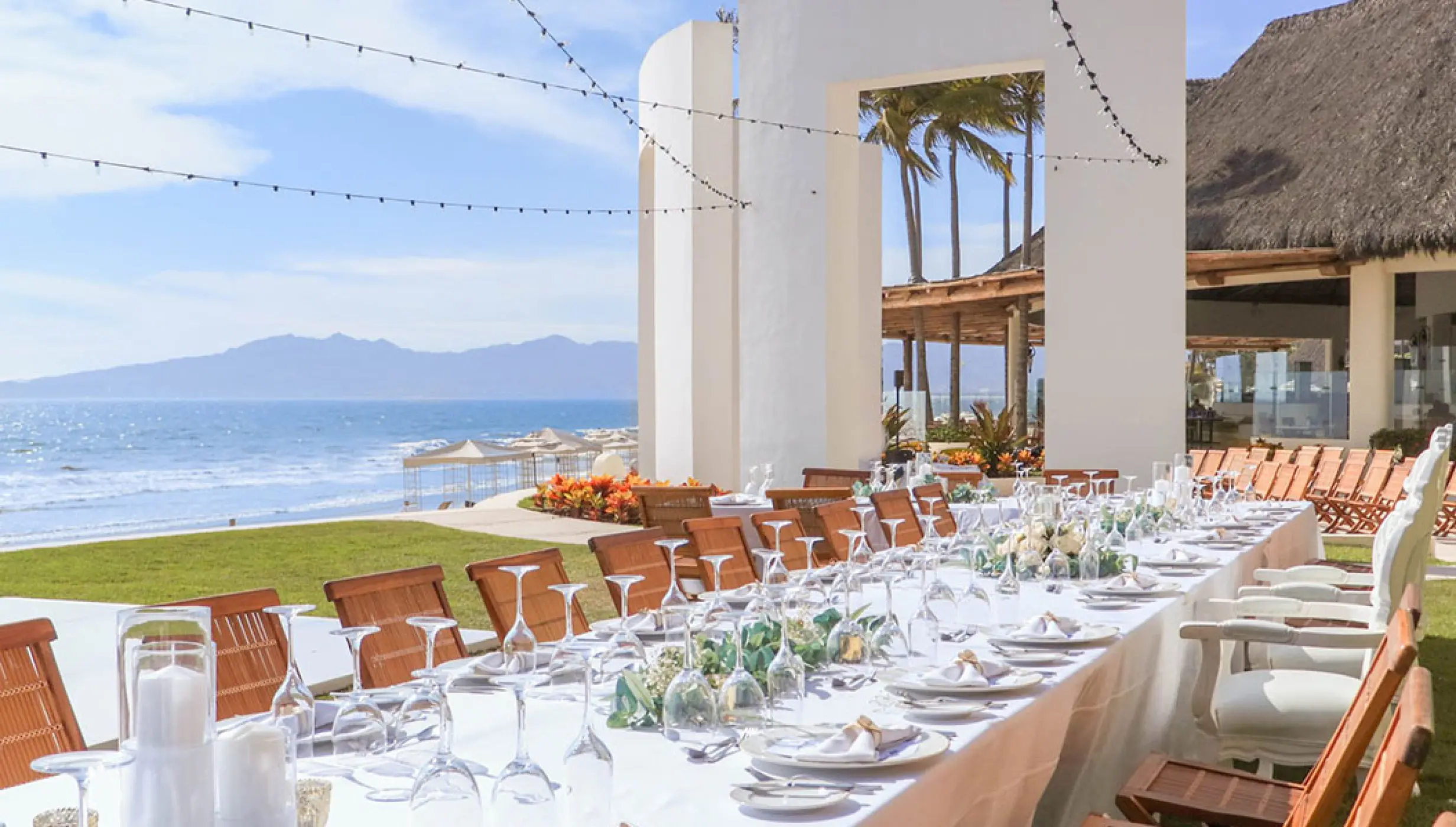 Outdoor wedding reception with a long dining table overlooking the ocean at Grand Velas Riviera Nayarit, Puerto Vallarta