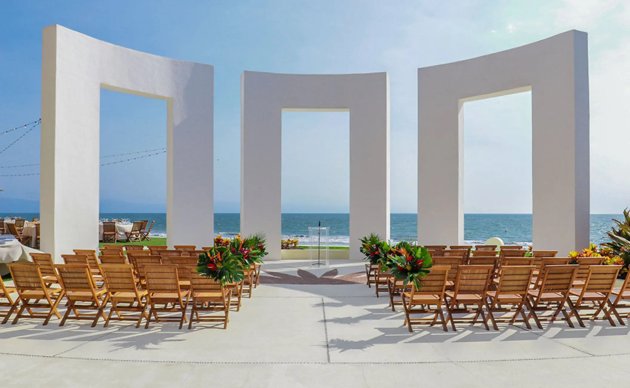 Terrace wedding ceremony with wooden chairs and white arches at Grand Velas Riviera Nayarit, Puerto Vallarta