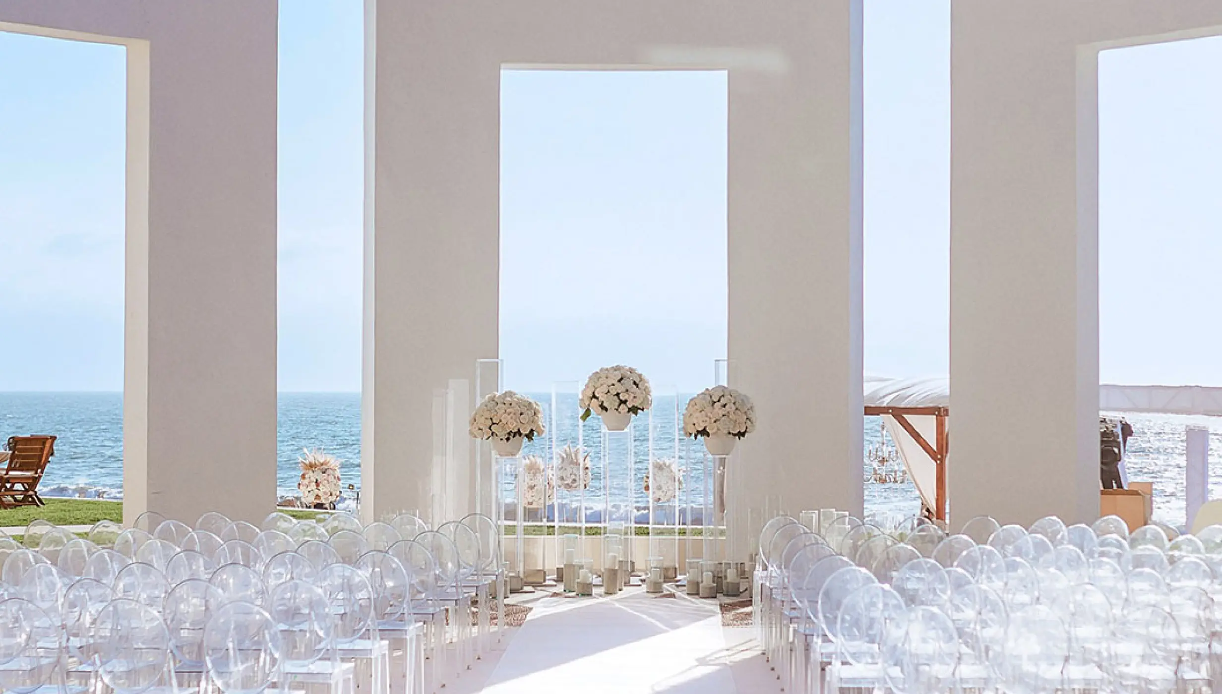 Terrace wedding ceremony with clear ghost chairs and floral pillars at Grand Velas Riviera Nayarit, Puerto Vallarta