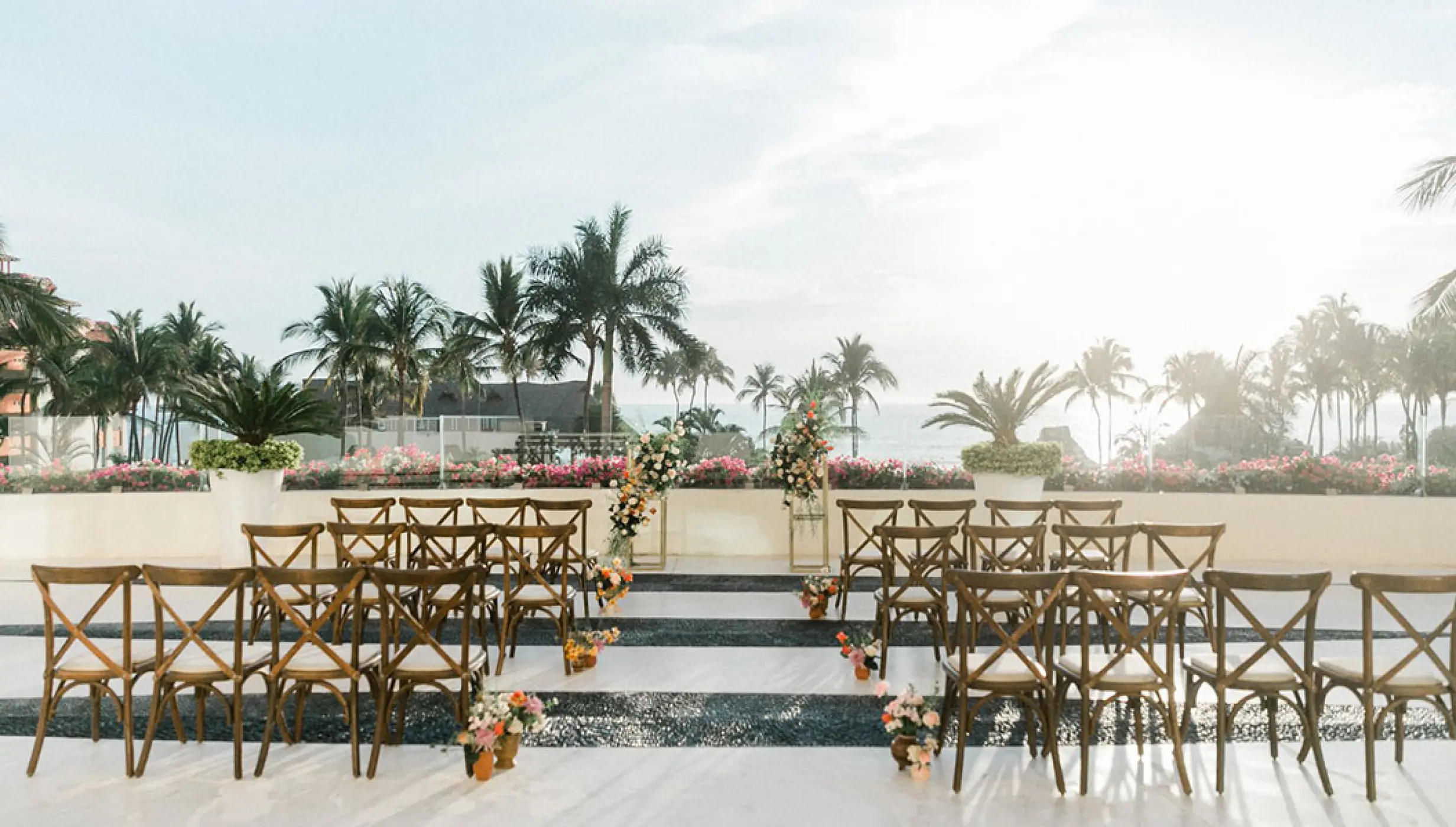 Sky terrace wedding ceremony setup with wooden cross-back chairs at Grand Velas Riviera Nayarit, Puerto Vallarta
