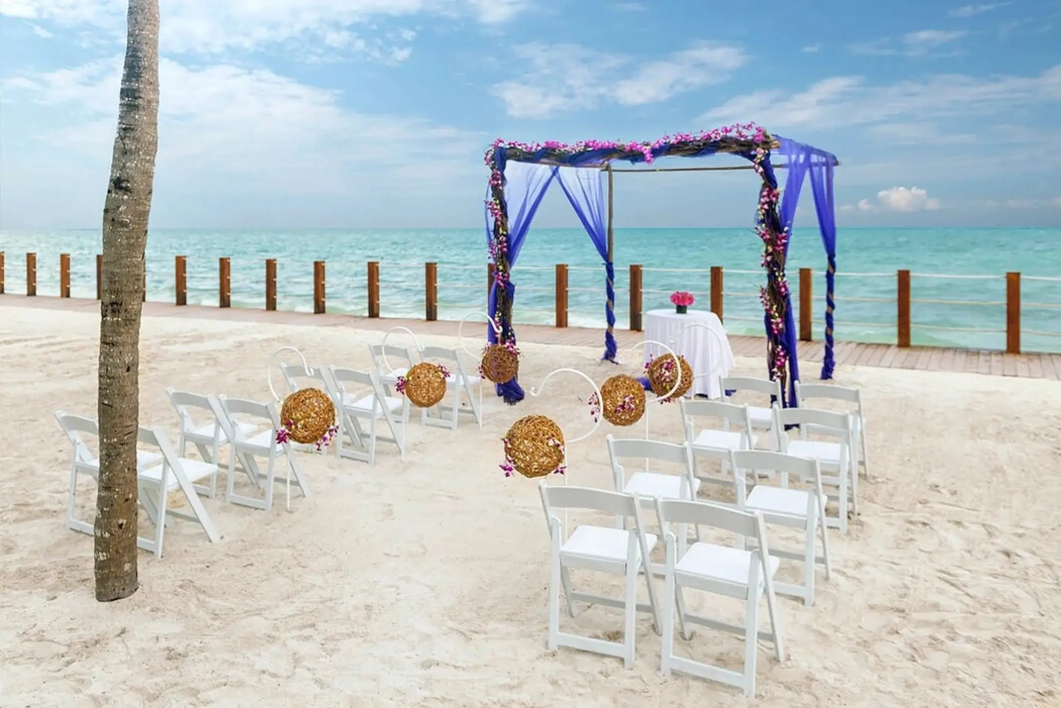 Beach wedding ceremony with purple floral huppah at Ocean Maya Royale, Riviera Maya