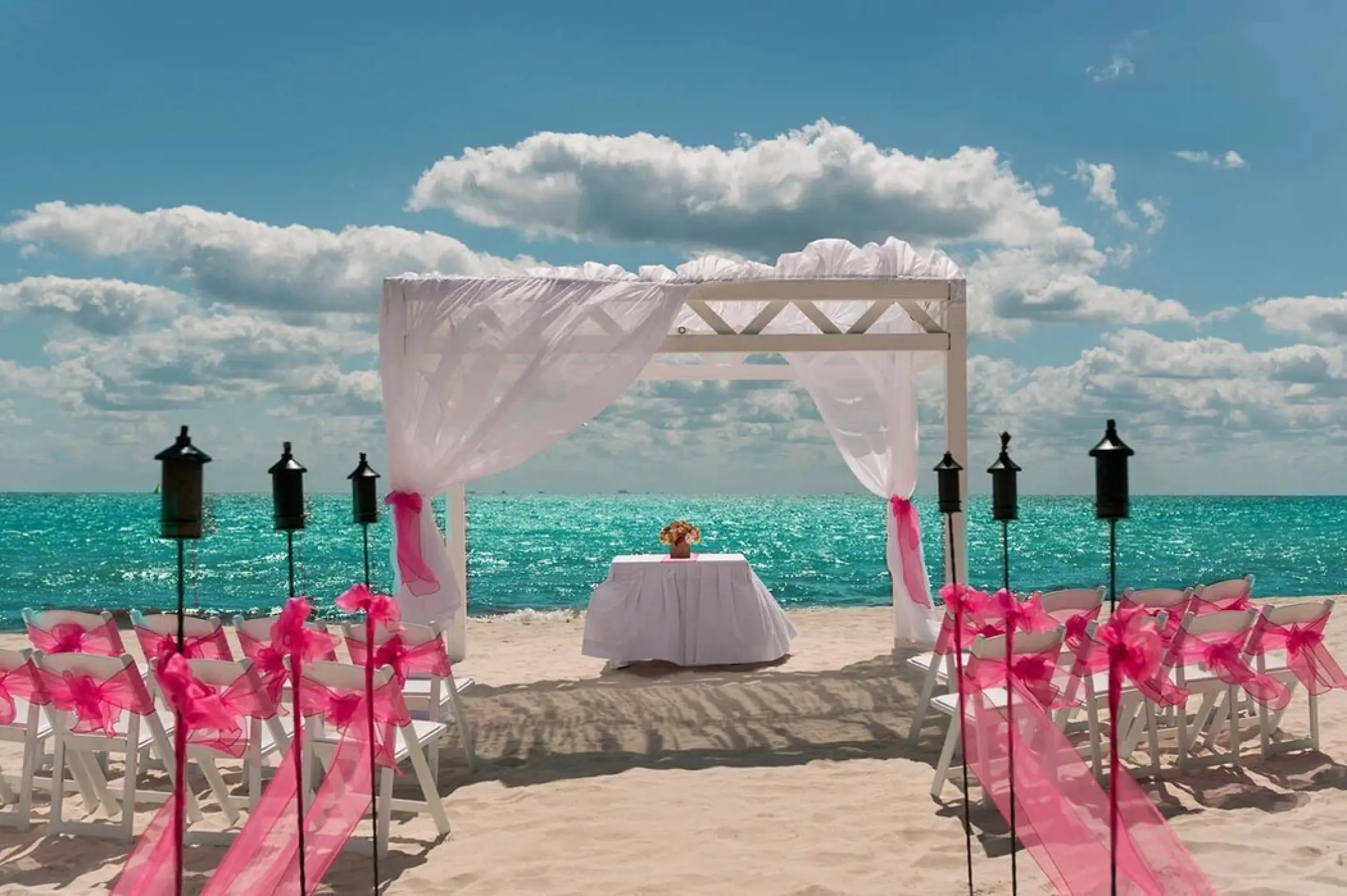 Beachfront wedding ceremony setup with pink bows at Ocean Maya Royale, Riviera Maya