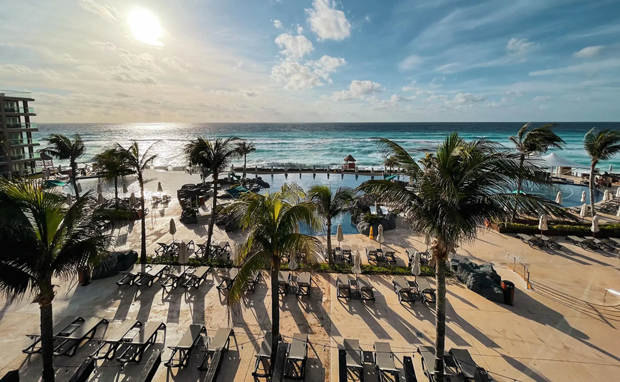 Sunrise over the oceanfront pools and palm trees at Hard Rock Cancun, Cancun