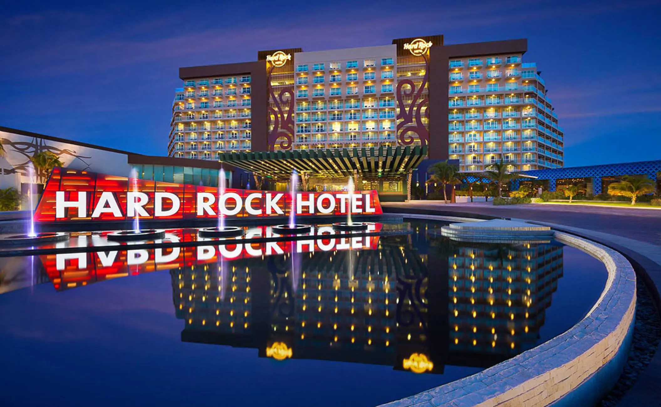 Illuminated Hard Rock Hotel Cancun sign and fountains at night, Cancun