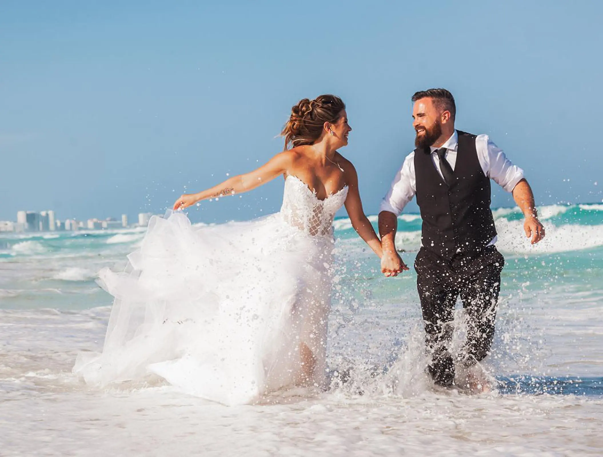 Bride and groom running through waves at Hard Rock Cancun, Cancun