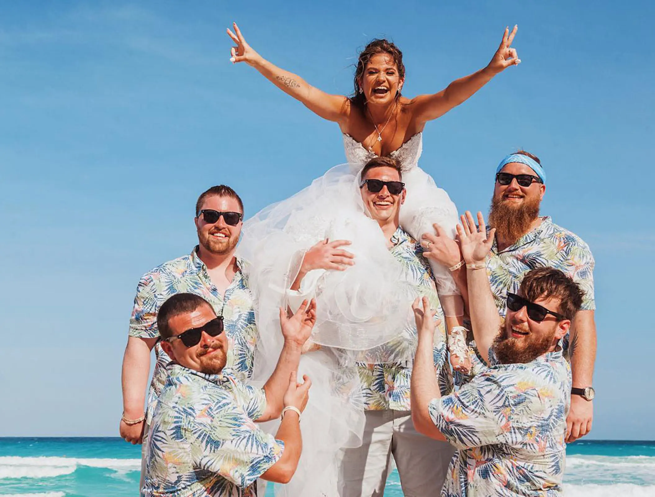 Groomsmen lifting the bride during a beach wedding party at Hard Rock Cancun