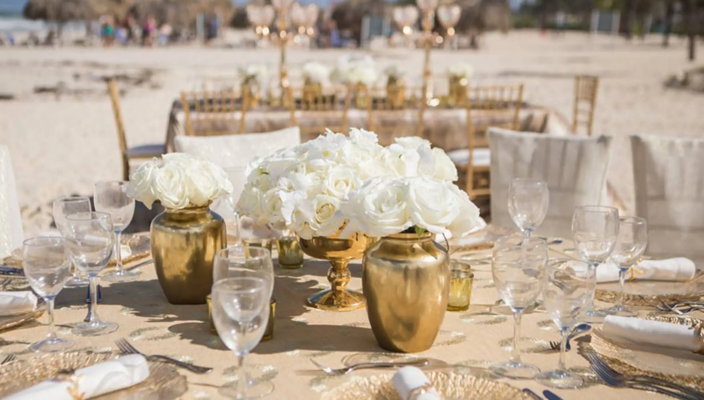 White roses in gold vases at a beach wedding reception at Hard Rock Vallarta, Puerto Vallarta