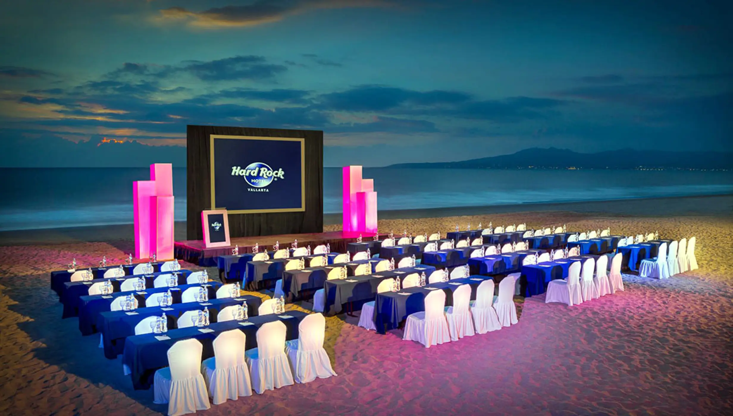 Beachfront wedding reception setup with lit tables and pink accents at Hard Rock Vallarta, Puerto Vallarta