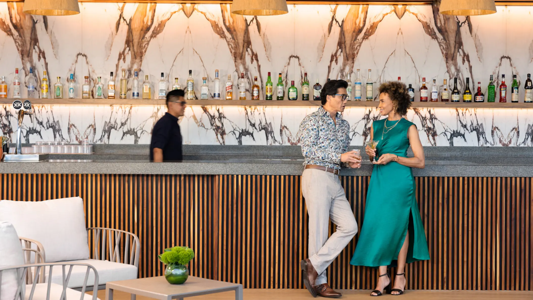 A couple enjoying drinks at the marbled bar at Hilton Cancun Mar Caribe