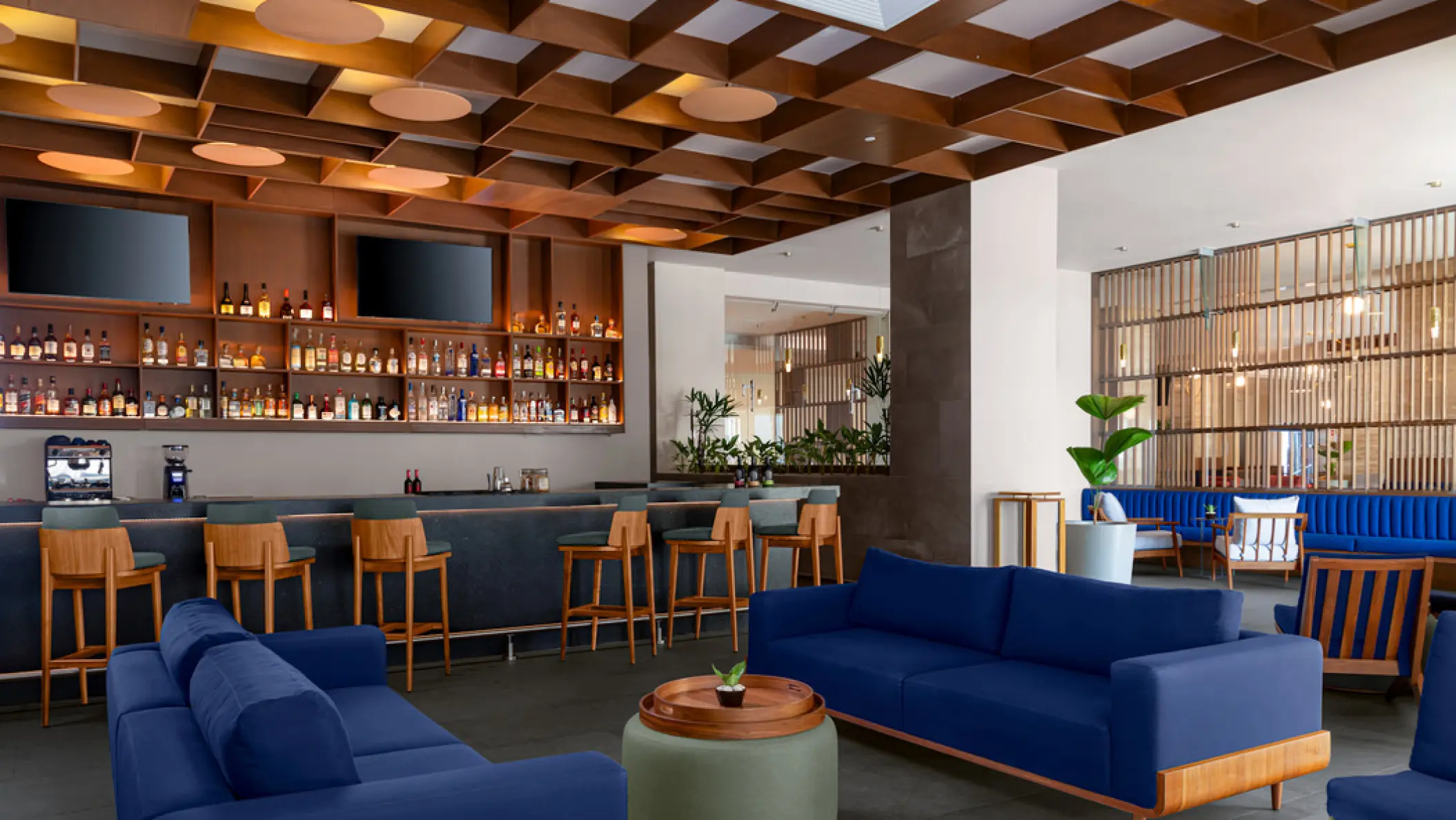 Indoor lobby bar with blue sofas and wooden stools at Hilton Cancun Mar Caribe