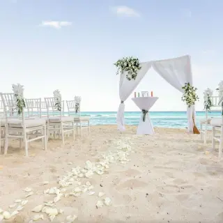 Beachfront wedding ceremony setup with white chairs and floral arch at Hilton Cancun Mar Caribe, Cancun