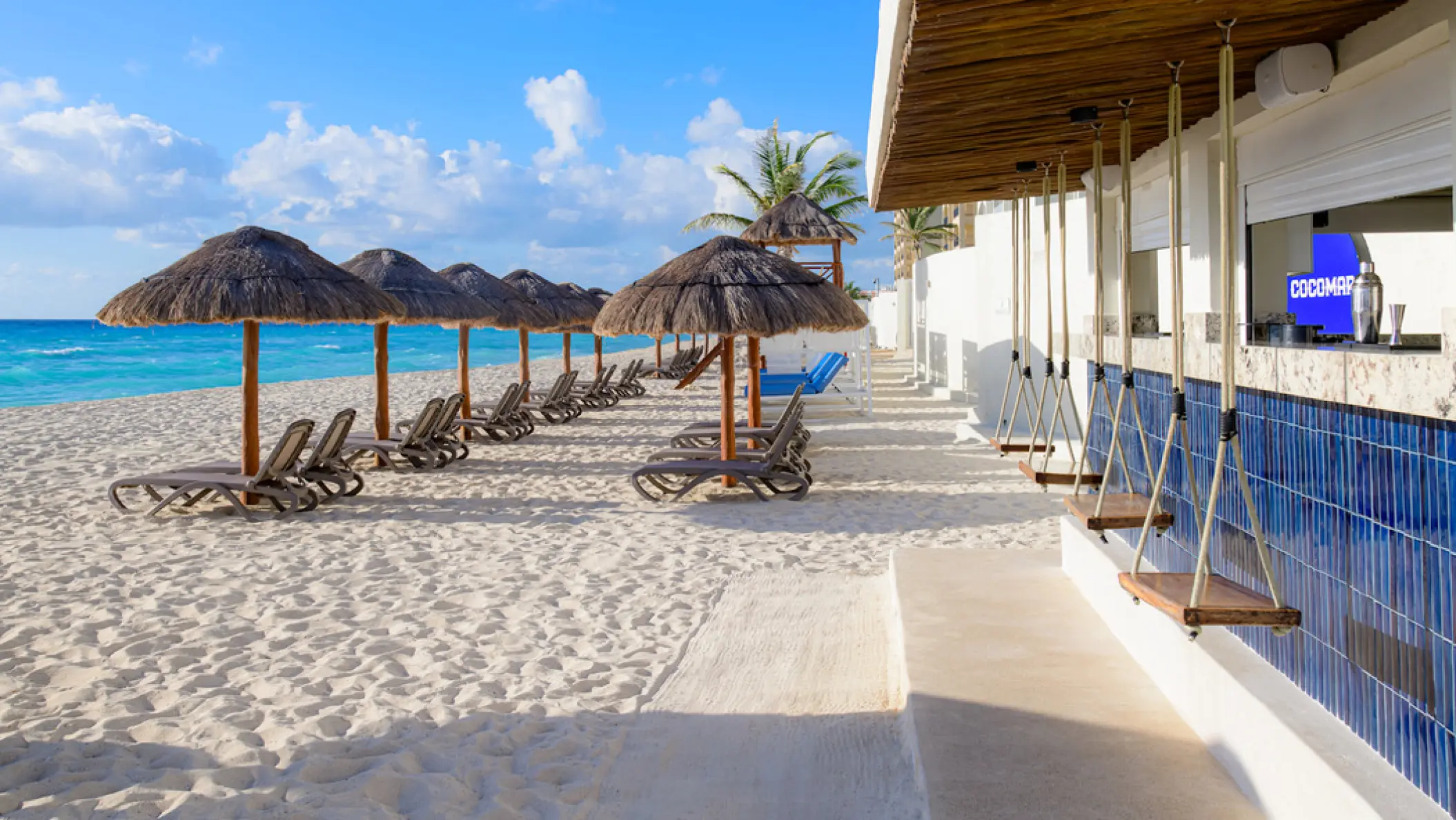 Cocomar beach bar with swing seating and thatched umbrellas at Hilton Cancun Mar Caribe, Cancun