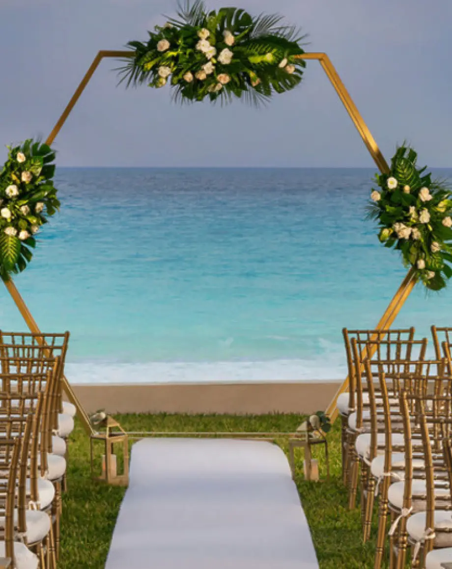 Hexagonal floral arch and gold chairs at a garden wedding ceremony at Hilton Cancun Mar Caribe, Cancun