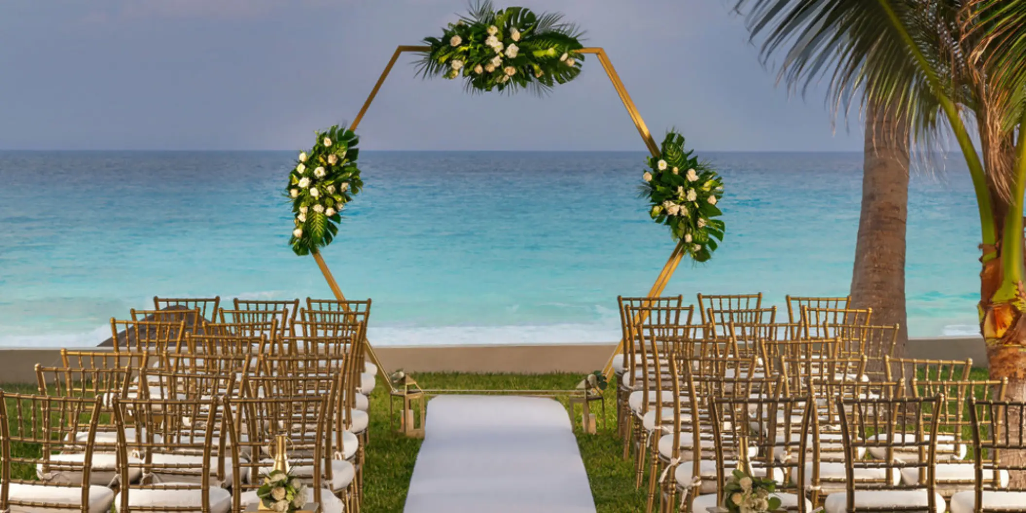 Hexagonal floral arch and gold chairs at a garden wedding ceremony at Hilton Cancun Mar Caribe, Cancun