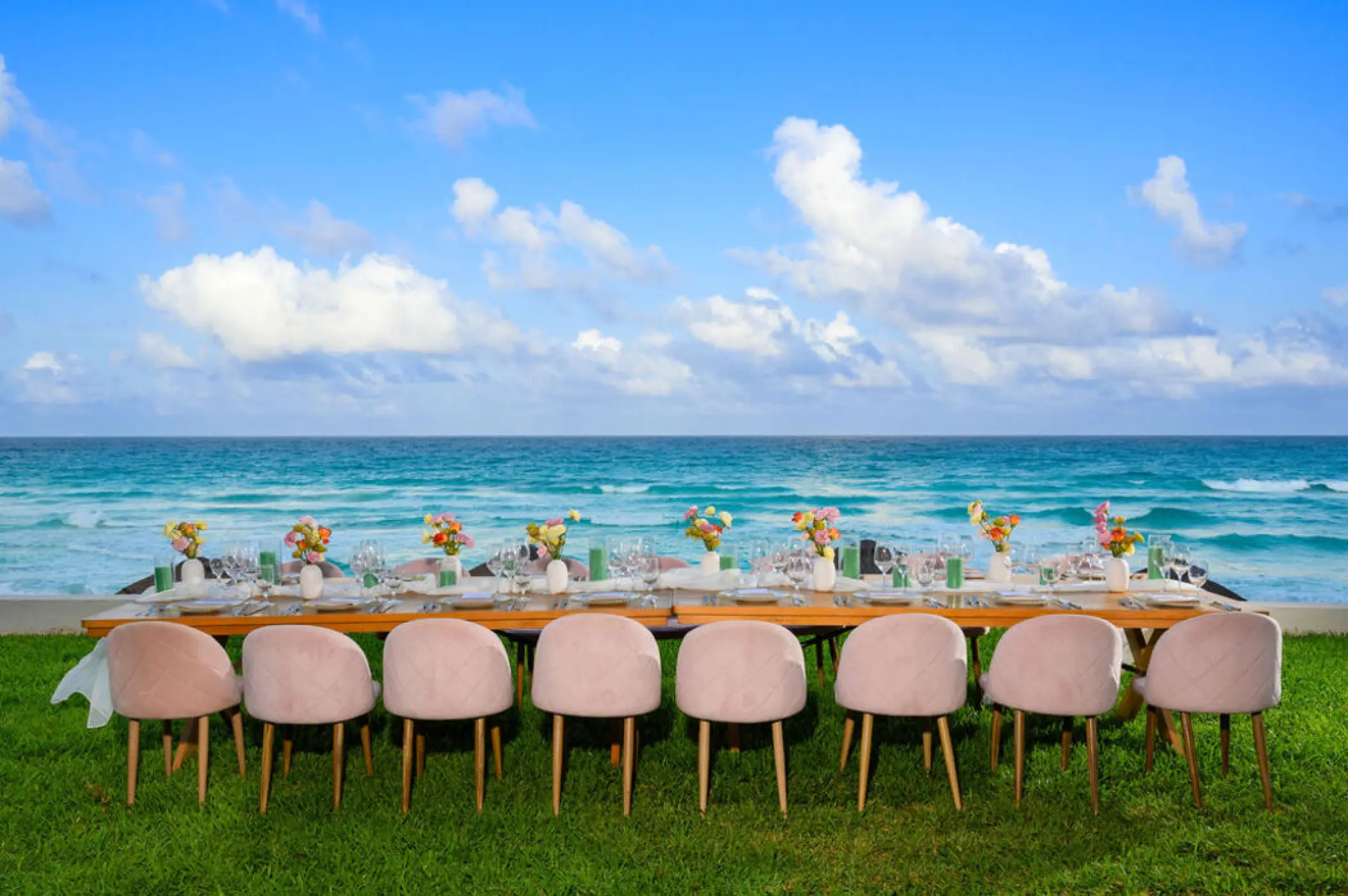 Oceanfront wedding reception table with pink chairs on the lawn at Hilton Cancun Mar Caribe, Cancun