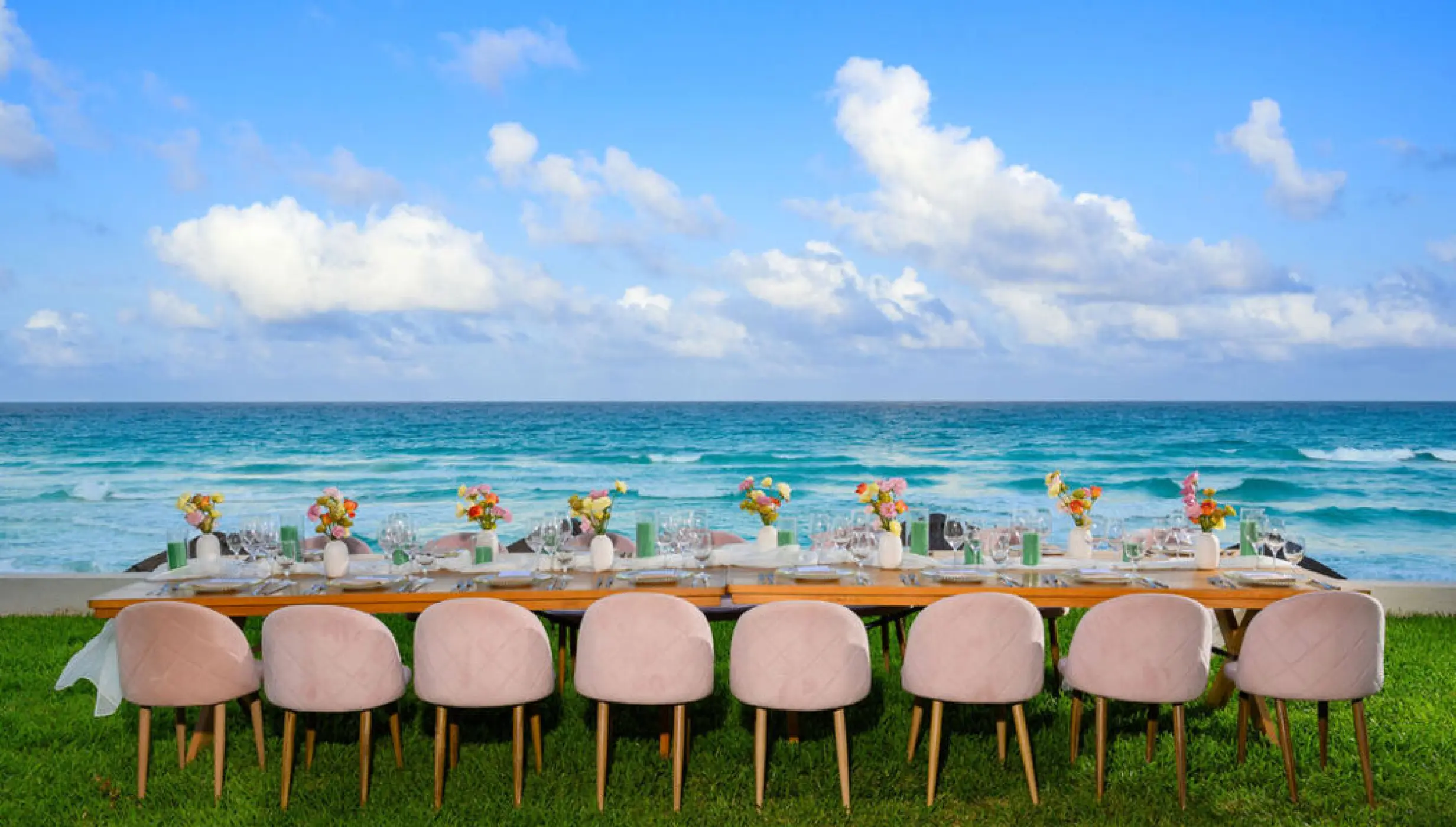Oceanfront wedding reception table with pink chairs on the lawn at Hilton Cancun Mar Caribe, Cancun