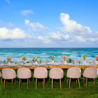 Oceanfront wedding reception table with pink chairs on the lawn at Hilton Cancun Mar Caribe, Cancun