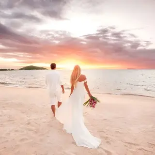 Bride and groom walking toward the ocean during sunrise at Hilton Playa del Carmen, Cancun