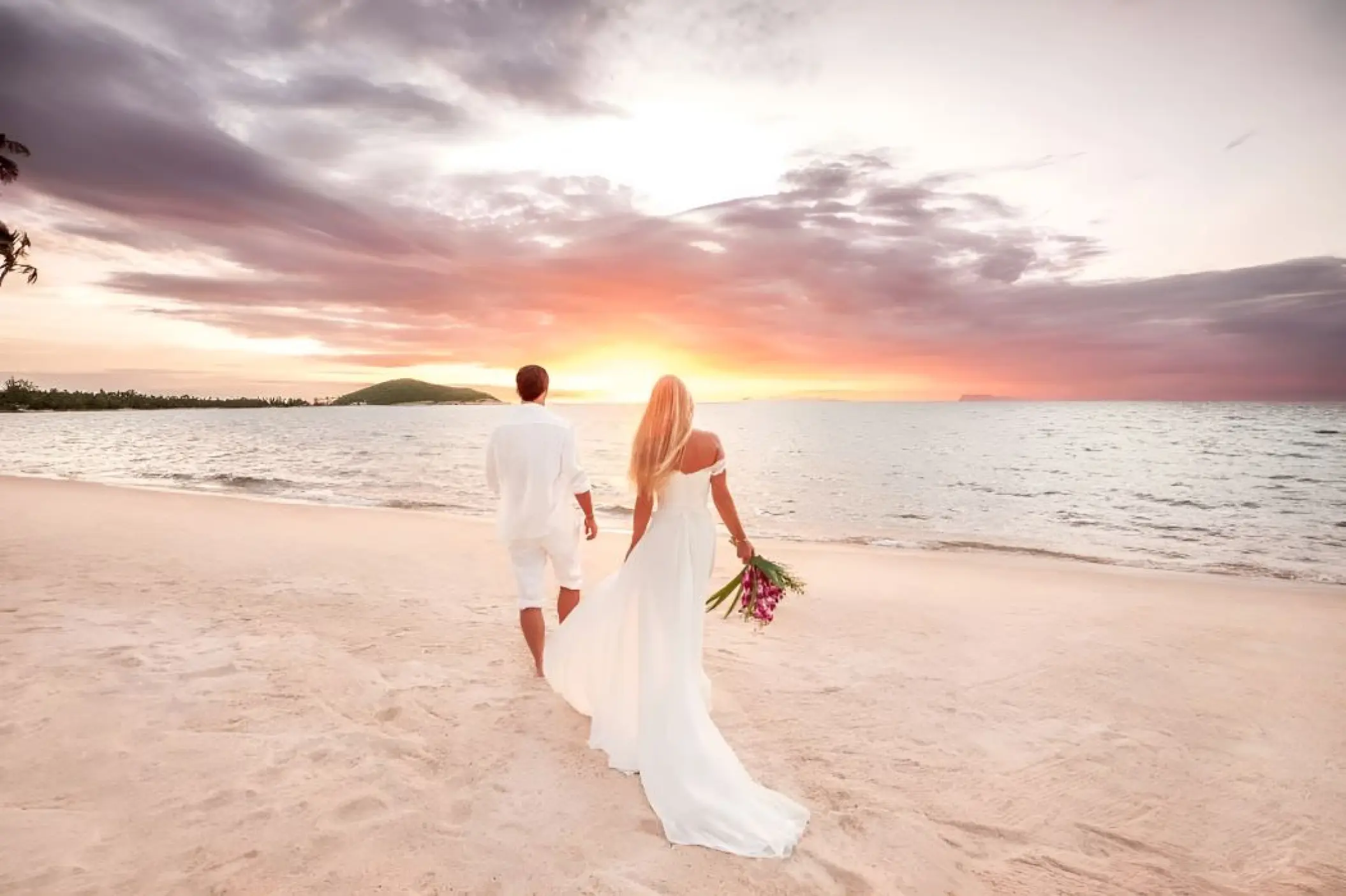 Bride and groom walking toward the ocean during sunrise at Hilton Playa del Carmen, Cancun