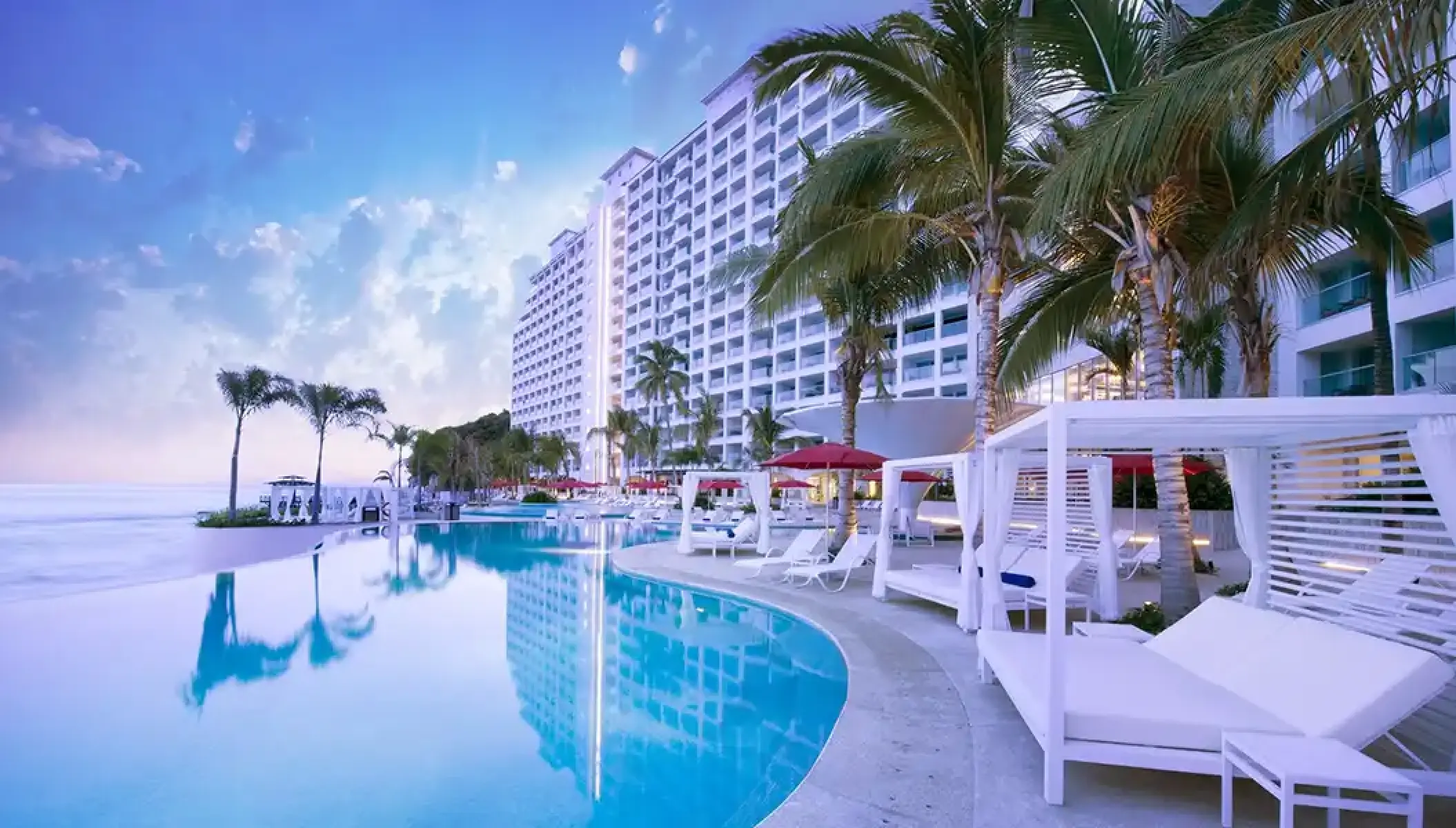 Hilton Vallarta Riviera infinity pool and white daybeds at dusk, Puerto Vallarta
