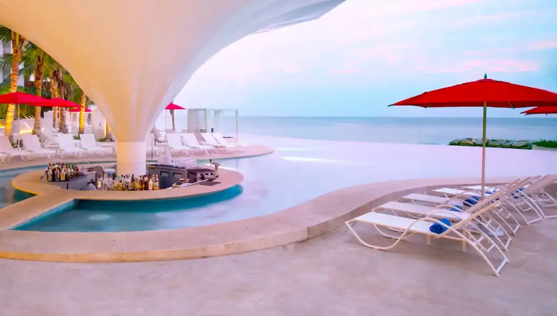 Swim-up bar and infinity pool with red umbrellas at Hilton Vallarta Riviera, Puerto Vallarta