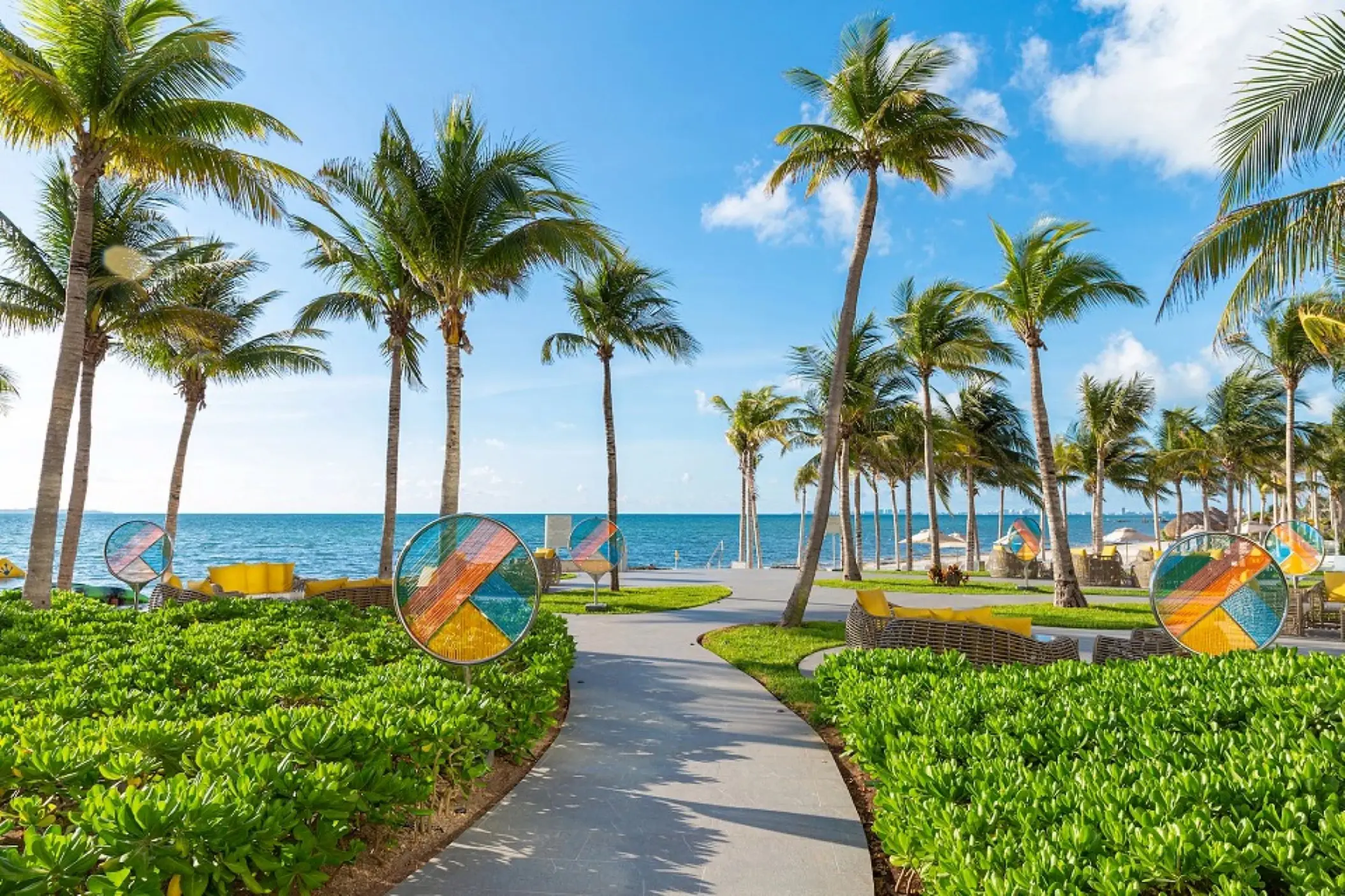 Palm tree-lined pathway overlooking the ocean at Hotel Mousai Cancun