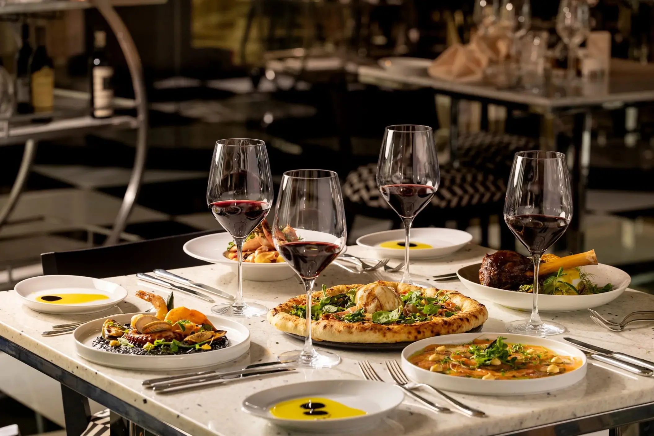 Plated gourmet dishes and glasses of red wine at Hotel Mousai Cancun