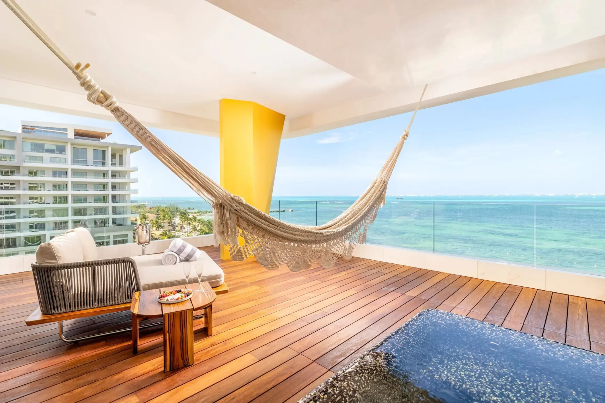 Hotel Mousai Cancun corner suite balcony with a hammock, lounge seating, and turquoise ocean views, Cancun