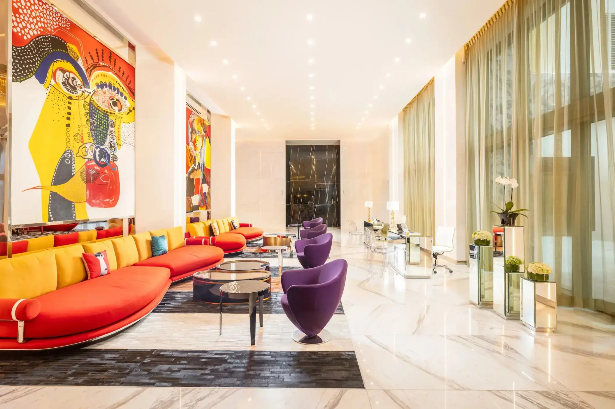 Modern lobby with red and yellow seating and abstract art at Hotel Mousai Cancun, Cancun