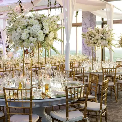 Sky room wedding reception with white floral centerpieces and gold chairs at Hotel Mousai Cancun
